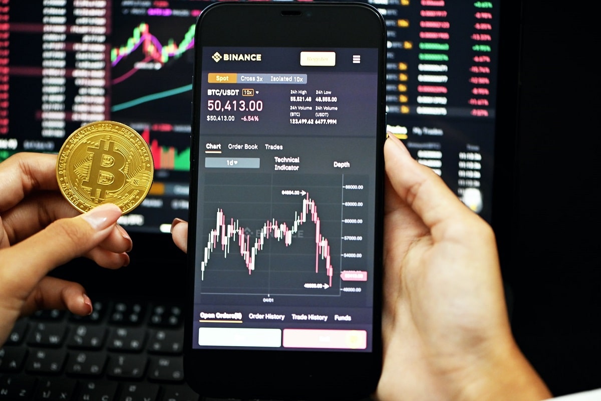 Aplicativo e site da Binance ao lado de bitcoin. Foto Kanchanara.