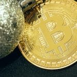 Moeda bitcoin próxima de uma bola prateada de natal