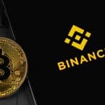 Moeda de Bitcoin ao lado de app da Binance.