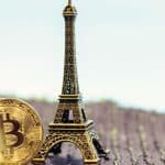 Moeda de Bitcoin ao lado de torre Eiffel.