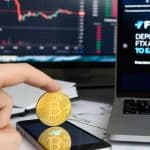Investidor segurando moeda de Bitcoin ao lado de site da FTX.