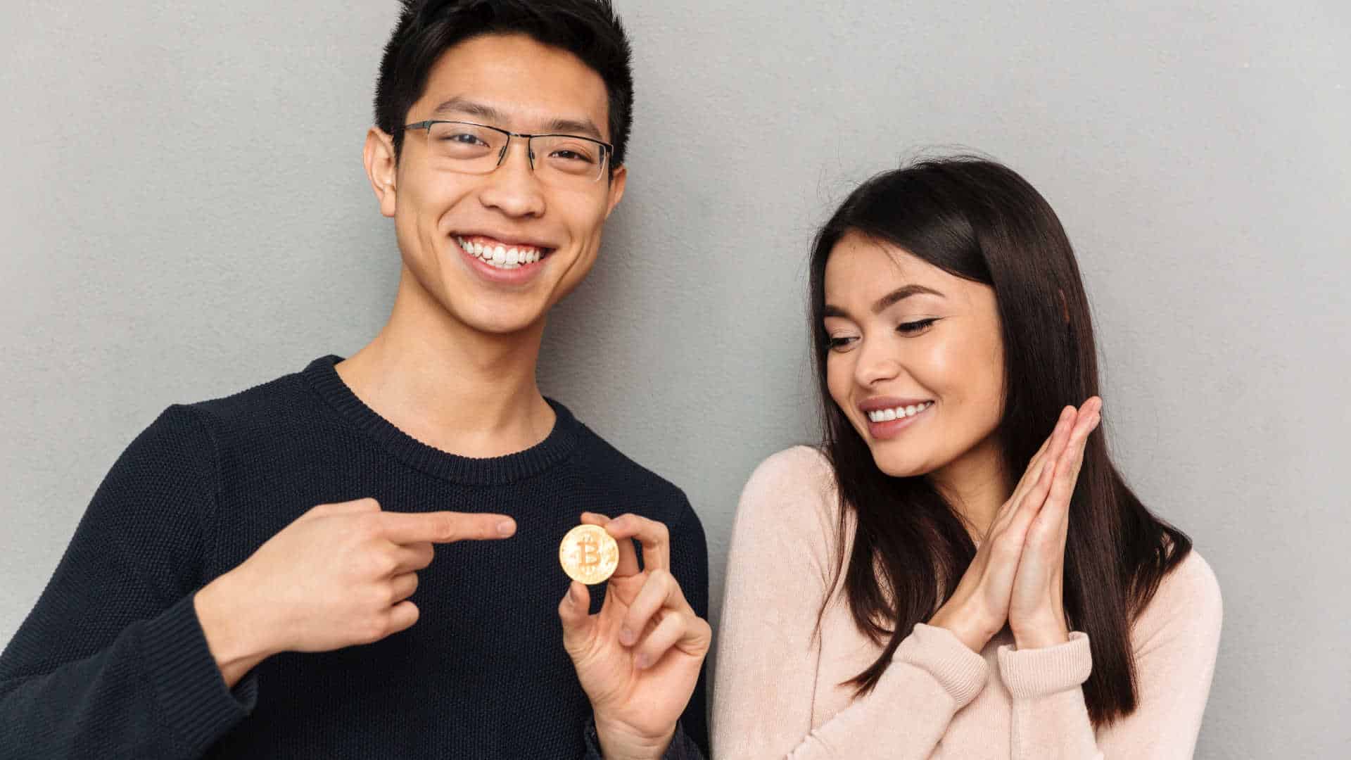 Mulher olhando para moeda de Bitcoin nas mãos de seu namorado.