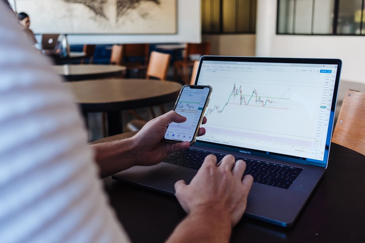 Gráfico em tela de celular e de computador com trader e investidores