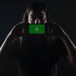 Mulher com segurando telefone com WhatsApp aberto em destaque