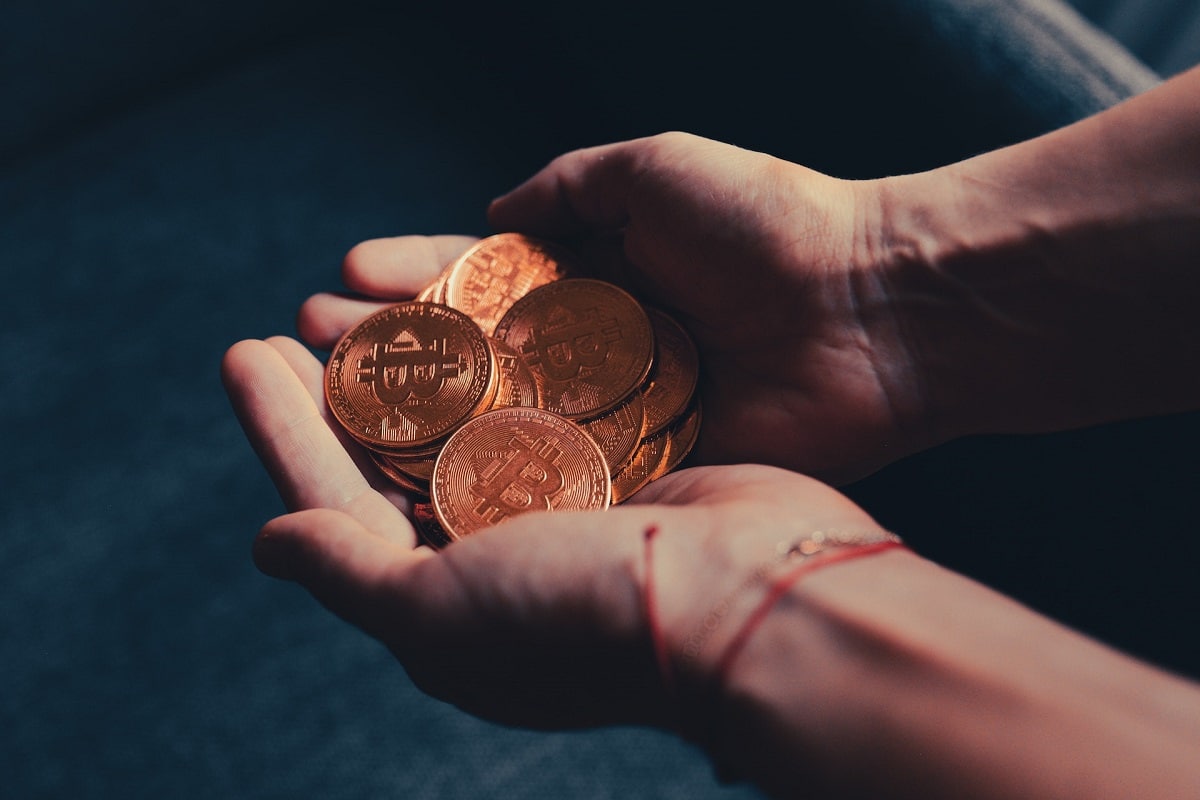 Mãos segurando muitos bitcoins