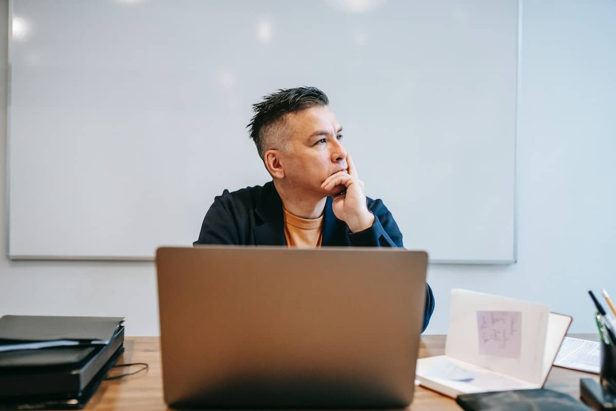 Homem pensando enquanto trabalha em seu computador