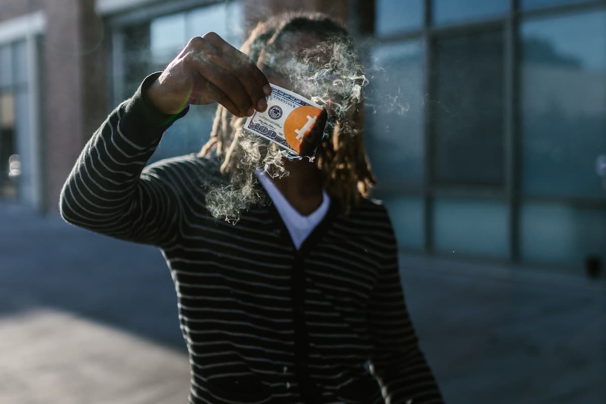 Homem segurando nota pegando fogo com símbolo do bitcoin