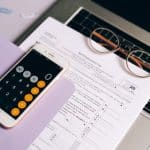 Calculadora em celular próxima de guia de imposto sobre notebook