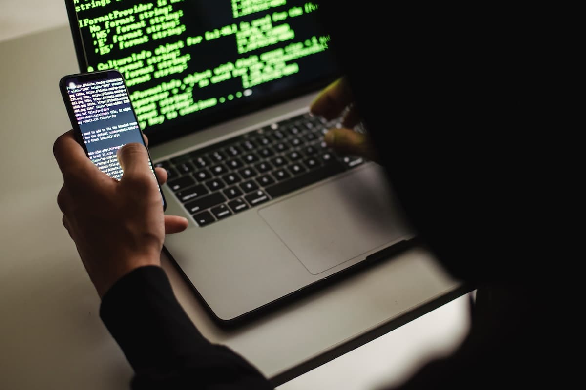 Hacker olhando mensagens em celular e notebook