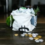 Saco de dinheiro próximo de criptomoedas em mesa