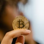 Investidor segurando moeda de Bitcoin. Foto de Tima Miroshnichenko/Pexels.