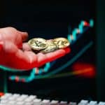 Investidor segurando bitcoin próximo de gráfico em alta