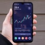Pessoa segurando celular com cotação de criptomoedas golpe