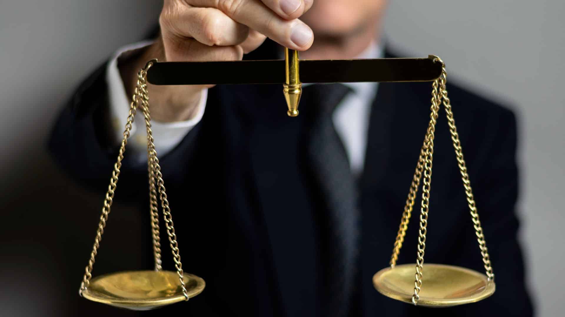 Homem segurando balança da justiça criptomoedas empresa