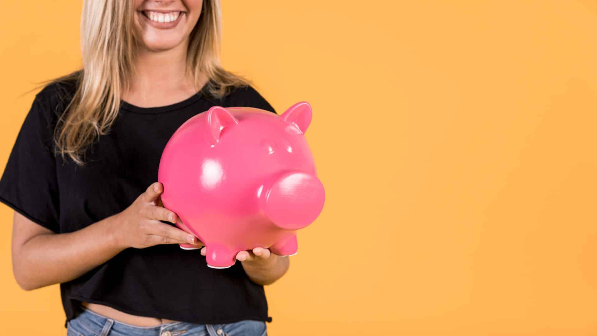 Jovem segurando porquinho em alusão a poupança criptomoedas