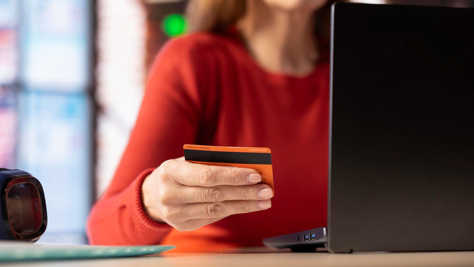 Mulher segurando cartão laranja itaú criptoativos