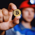 Minerador segurando moeda de bitcoin