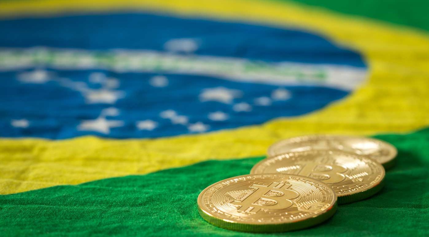 Bandeira do Brasil e moedas de bitcoin.