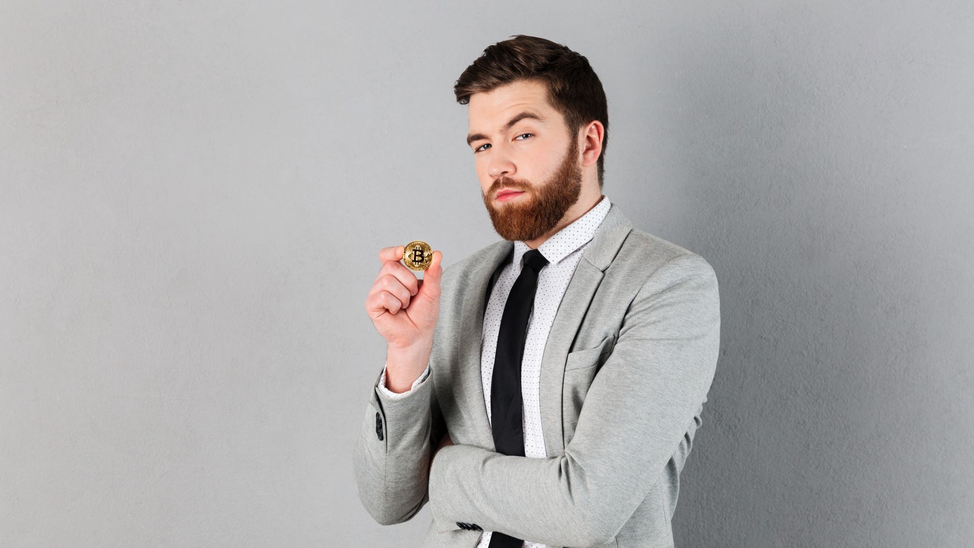 Homem com olhar desconfiado ao segurar bitcoin Coinbase Brasil