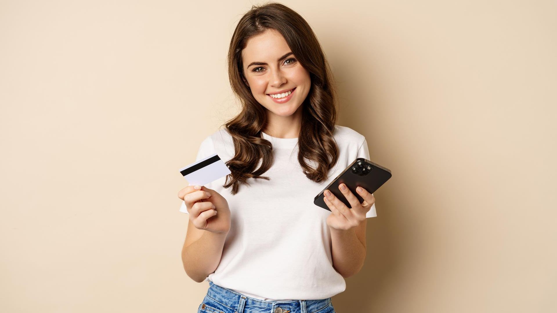 Mulher segurando cartão e celular sorrindo Ripple vai implementar liquidação em stablecoin após parceria com Mastercard, WebBank e Gemini