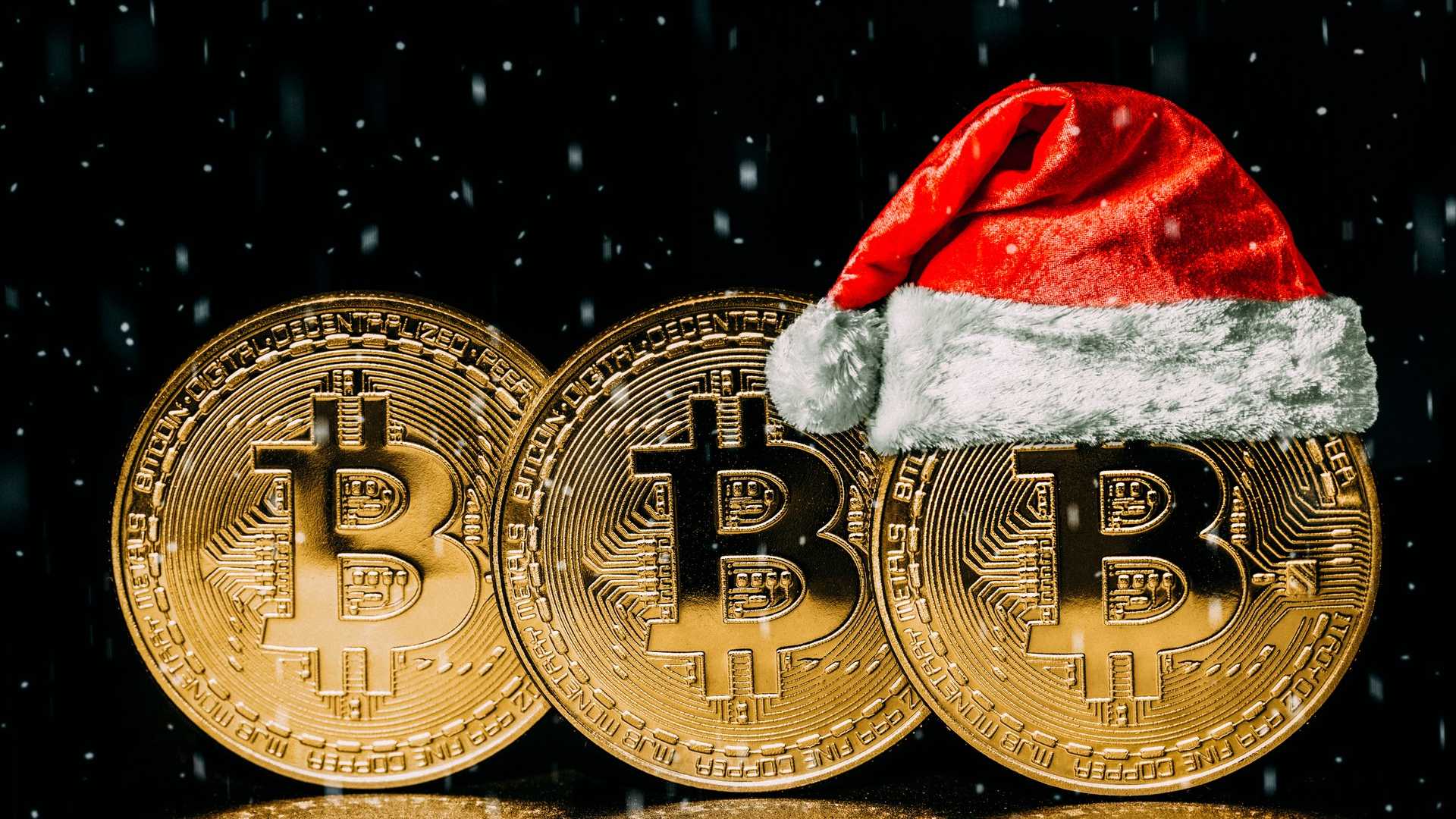 Bitcoins um ao lado do outro, um com gorro de papai noel preço Natal