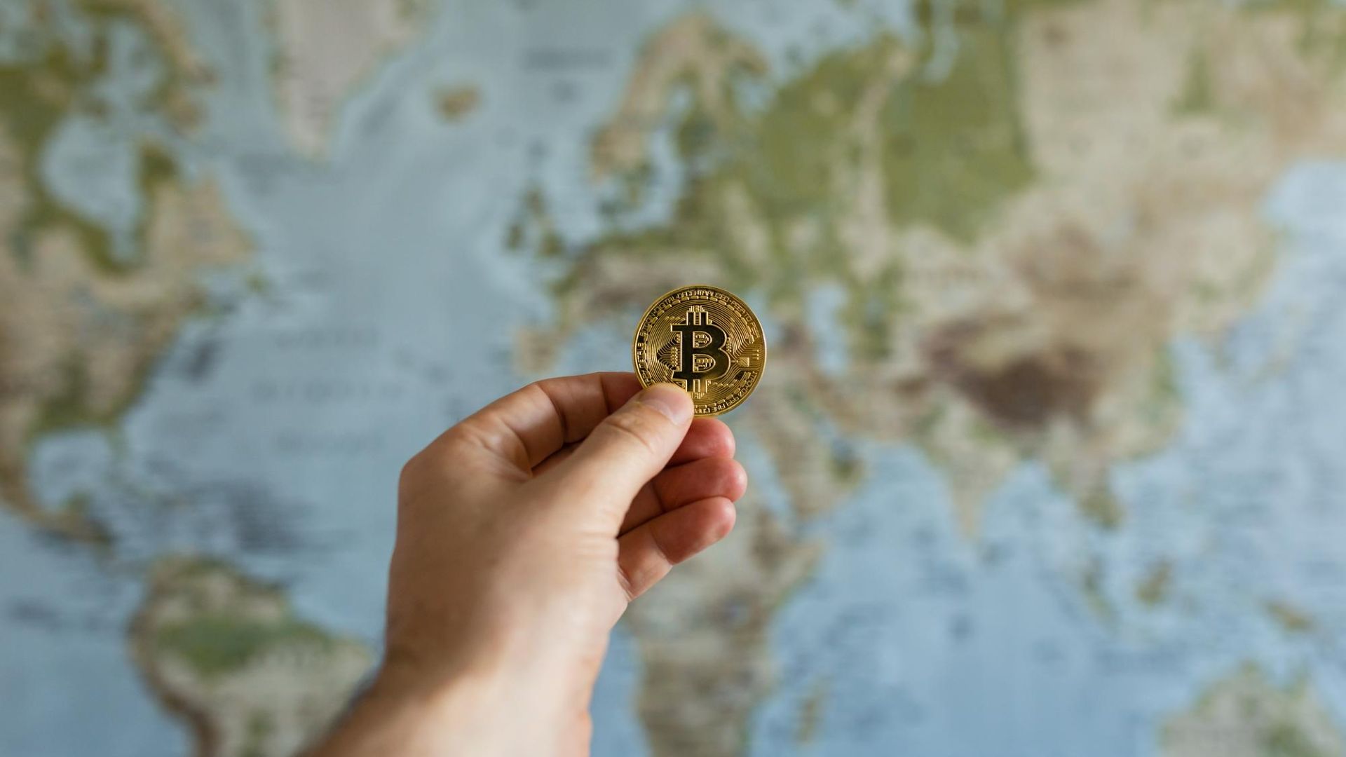 Mão segurando bitcoin na frente de um globo terrestre ministério público