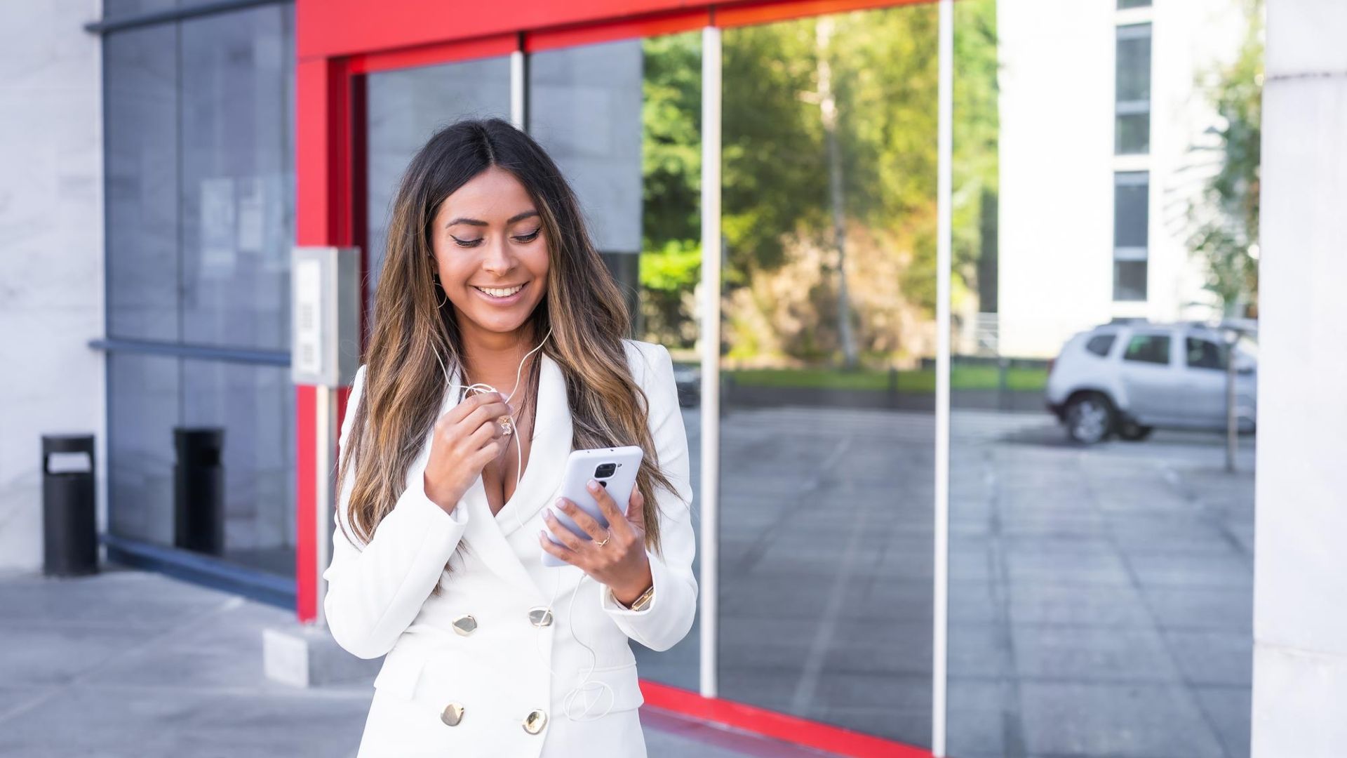 Mulher sorrindo na porta de agência bancária com fachada vermelha Santander Brasil criptomoedas