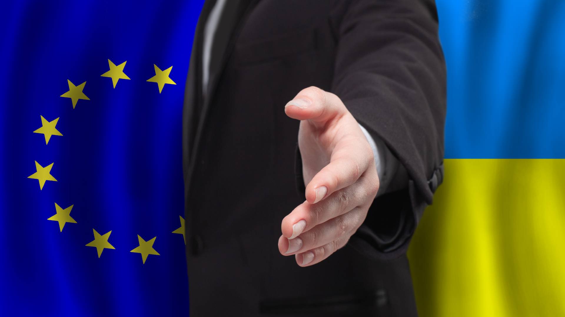 Mão extendida no meio de bandeira da União Europeia e da Ucrânia