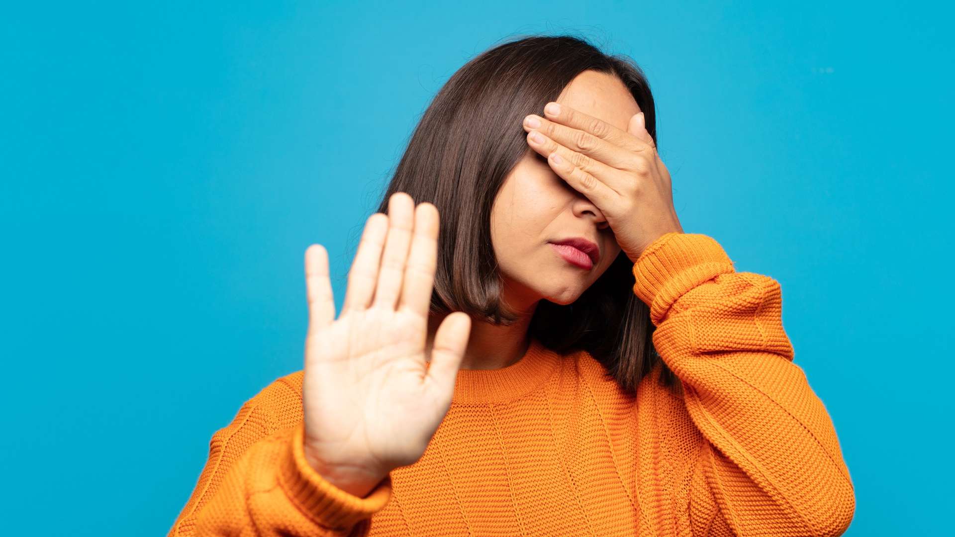 Mulher tampando seus olhos e fazendo sinal de pare em foto