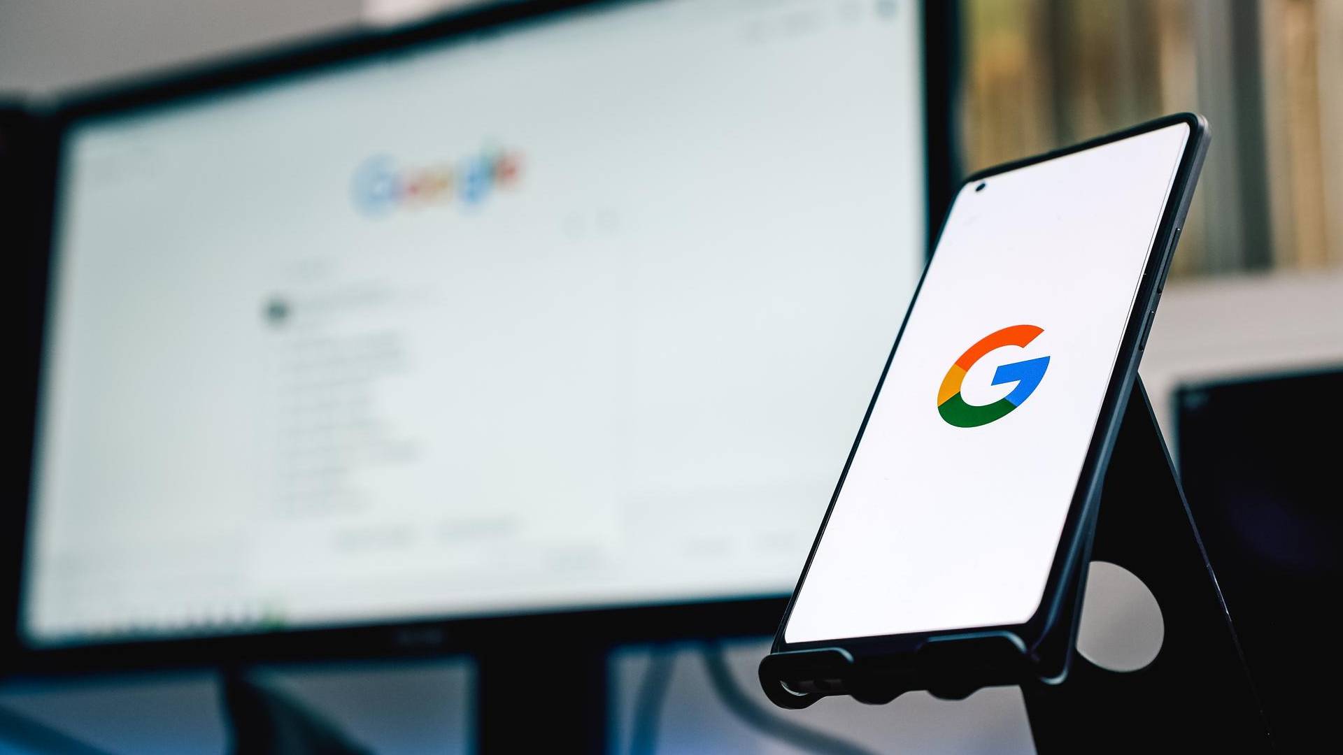 Google Finanças atualiza no Brasil com novas opções para investidores de criptomoedas Símbolo do Google em smartphone e computador ao fundo