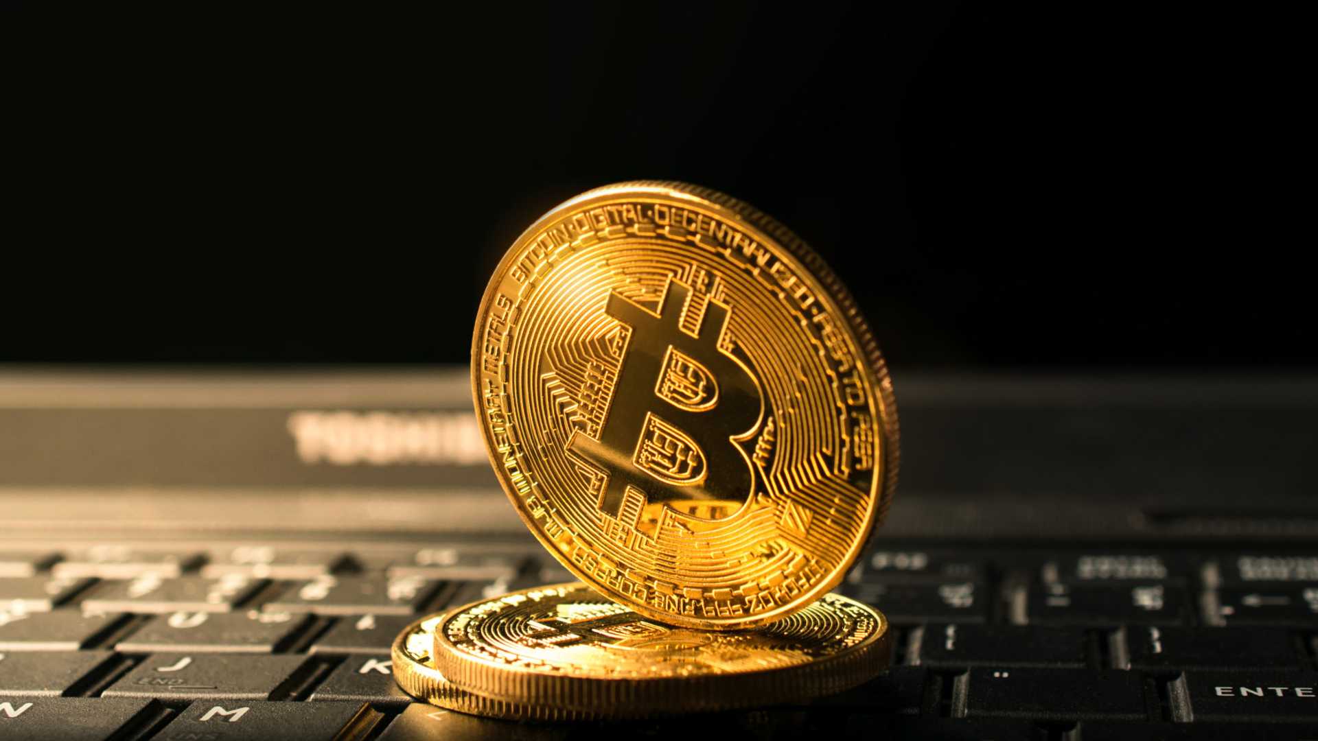 Bitcoin sobre computador apontando para baixo