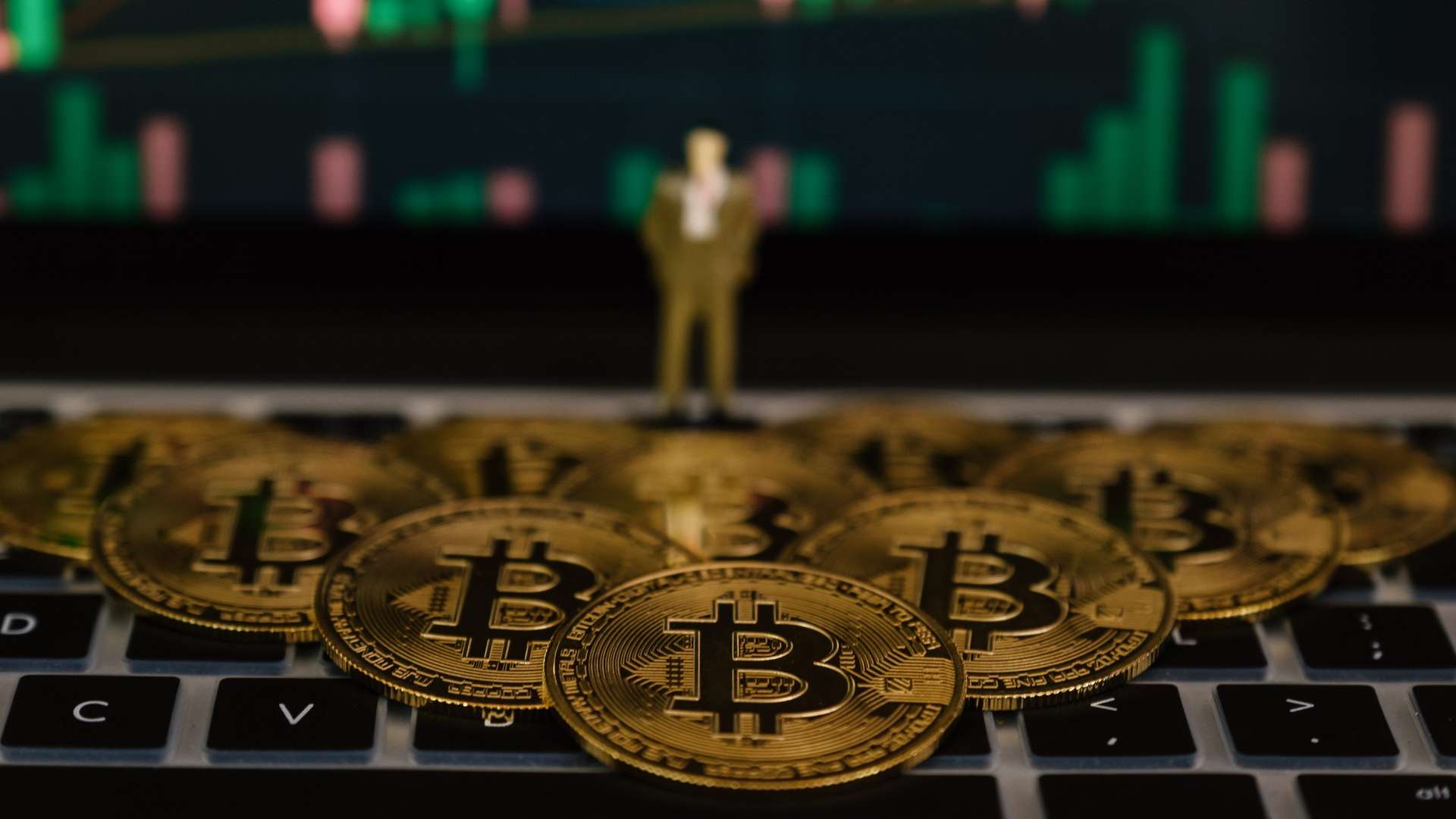 Gráfico do bitcoin com moedas simbólicas sobre mesa e miniatura de executivo observando Companhia brasileira compra 41 bitcoins e supera 3.800 unidades em sua posse