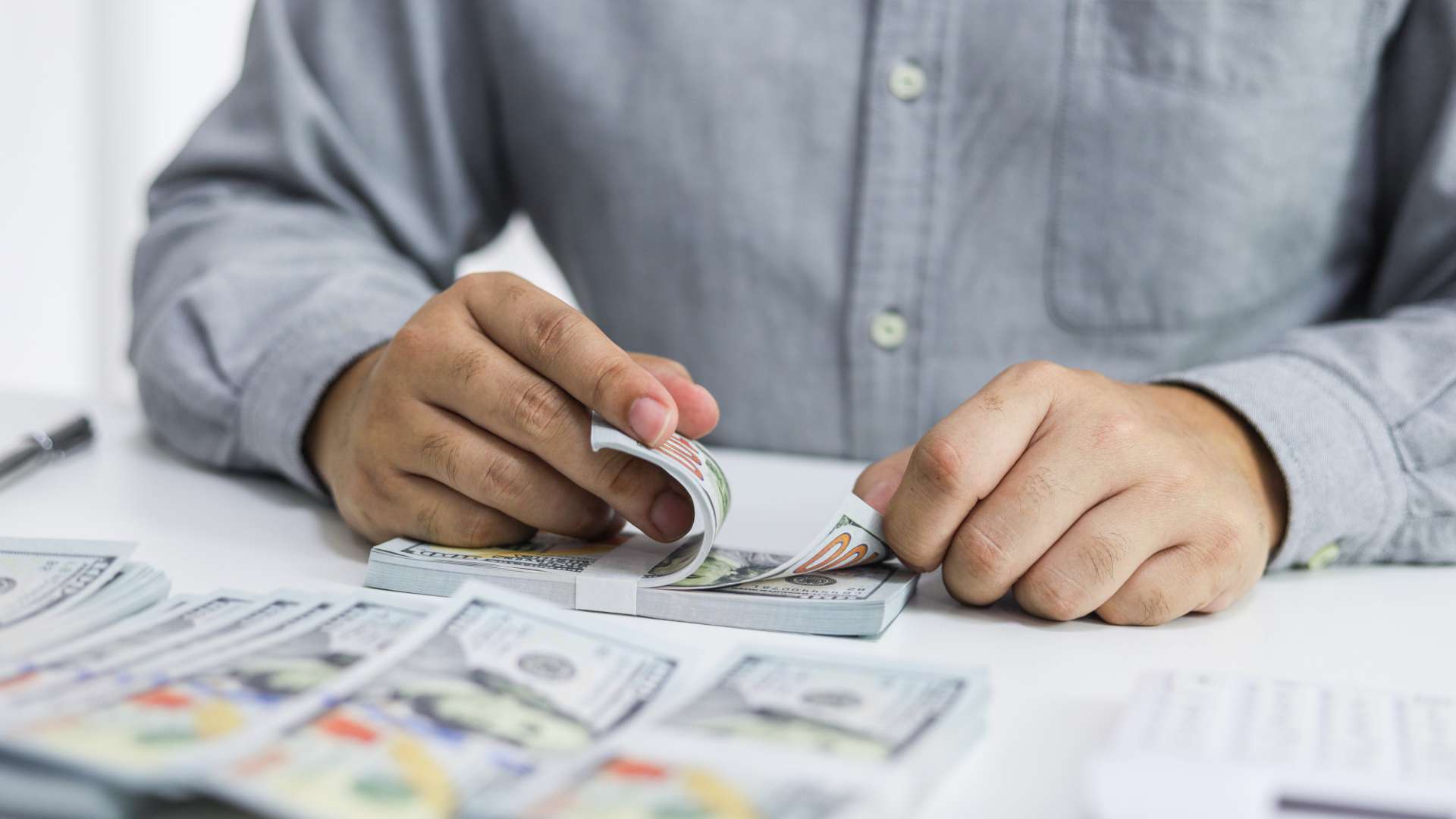 Homem contando dinheiro em notas de Dólar dólares Entidades do setor de criptomoedas alertam para riscos na nova regra da CVM