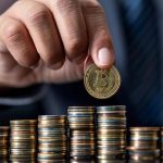 Bitcoin sobre montante de dinheiro na mesa, homem com terno ao fundo manipulando a moeda MP de São Paulo tem R$ 47 milhões em criptomoedas sob custódia